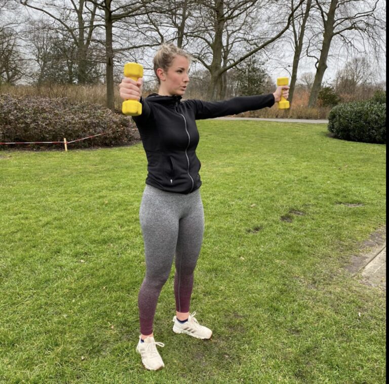 Vrouw in sportkleding traint buiten met gele kleine dumbells