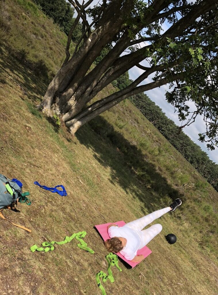 Vrouw in witte sportkleding traint buiten in de natuur
